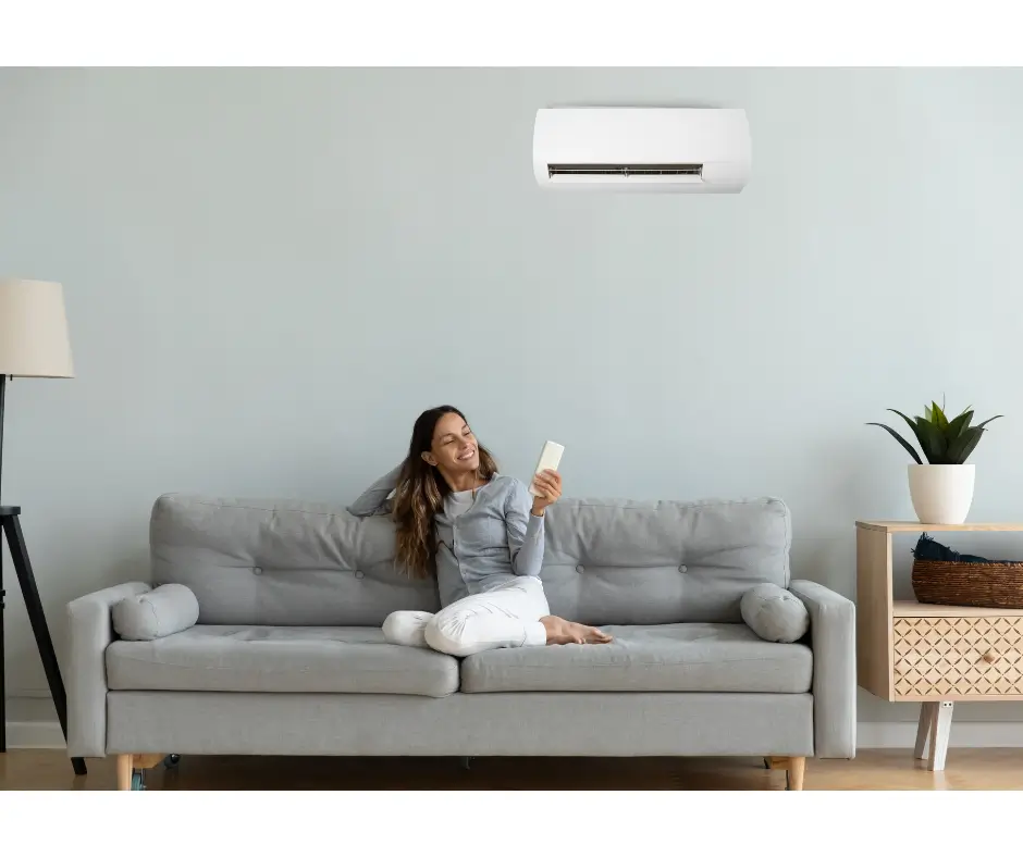 Mulher sentada no sofá em uma sala com um ar condicionado inverter